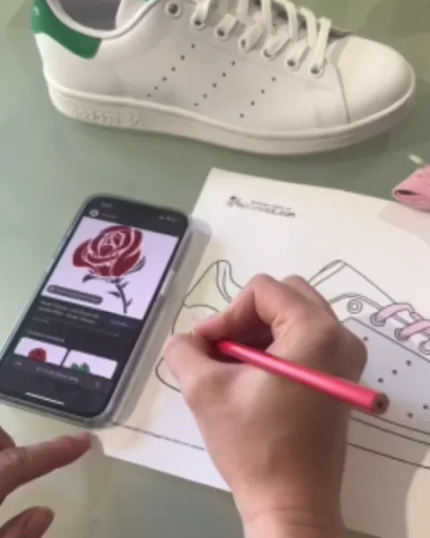 Une participante dessine une rose sur le gabarit de sa Stan Smith pendant l'atelier