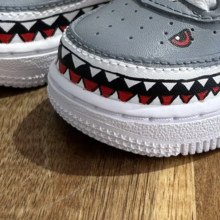 Gros plan d'une sneaker grise peinte de dents de requin et d'un œil